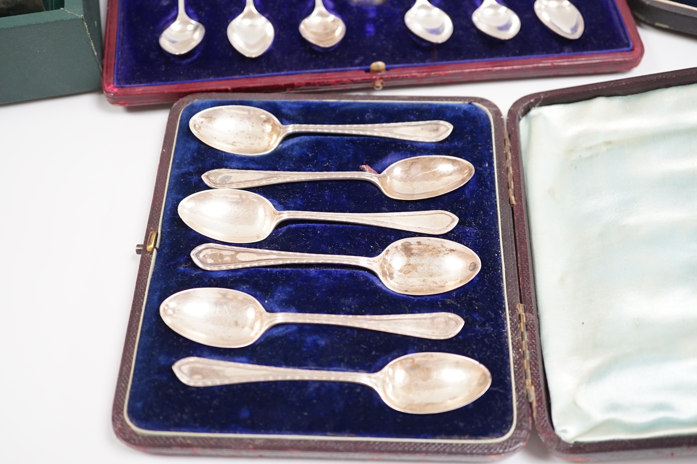 A cased George V silver christening trio, two cased sets of silver teaspoons, including set of twelve with sugar tongs and a cased modern silver mounted presentation cigarette box.